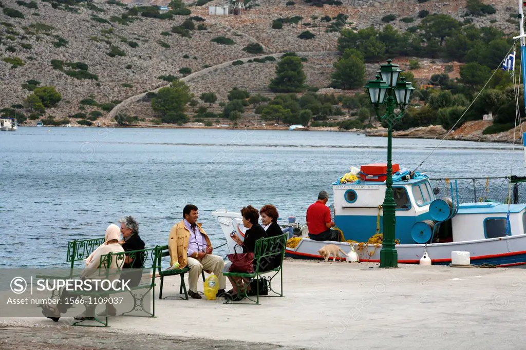 People and a fishing boat at the harbour in Panormitis, Symi, Greece
