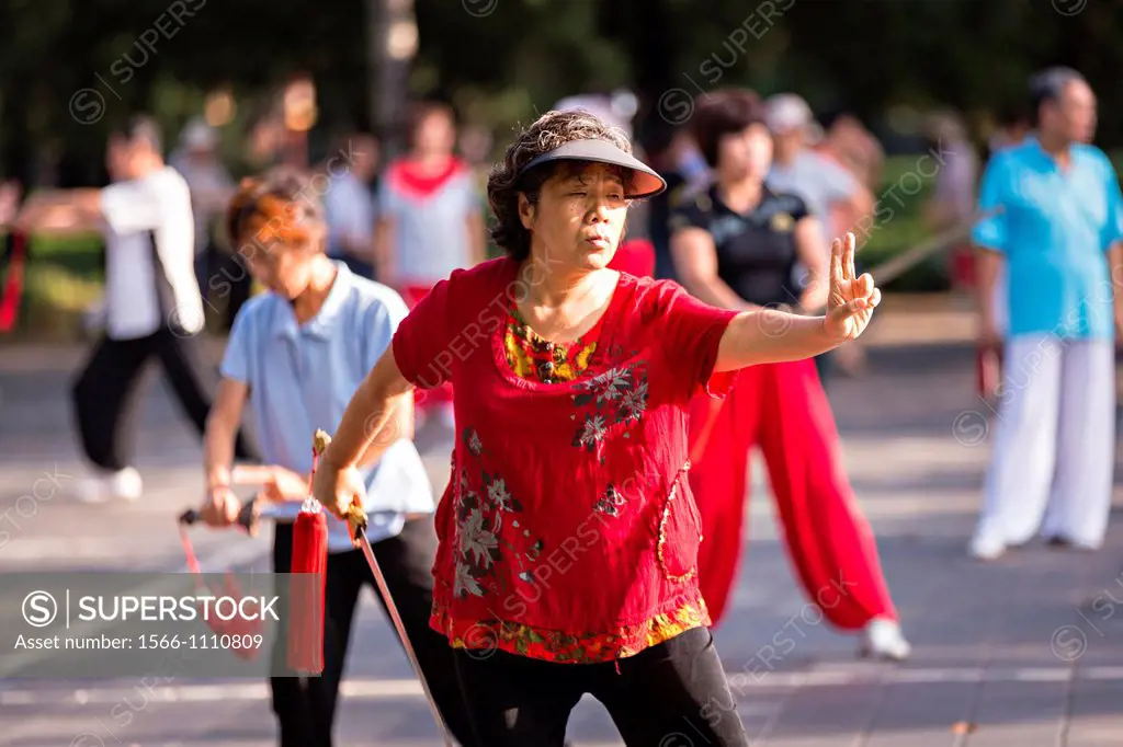 Elderly Chinese women practice sword martial arts exercise early morning at the Temple of Heaven Park during summer in Beijing, China