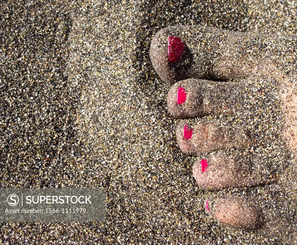 Woman feet half-buried in the sand