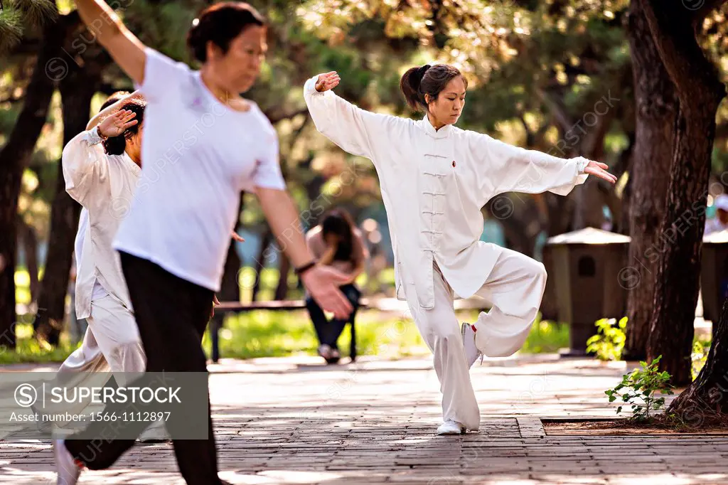 Chinese woman practices tai chi martial arts exercise early morning at the Temple of Heaven Park during summer in Beijing, China