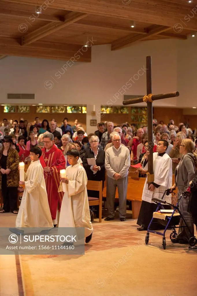 The congregation watches as young robed altar servers carry candles as they lead a procession carrying a cross on Holy Thursday at St. Timothy´s Catho...