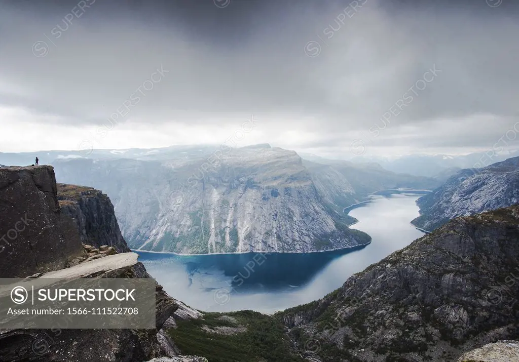 View of Trolltunga cliff and lake between mountains, picturesque landscape, beauty in nature, paradise on Earth, sunny day, Odda, Norway. cloudy day.