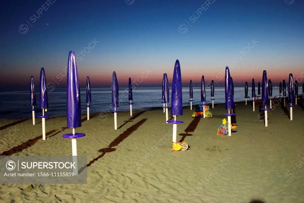 closed umbrellas on beach by the tyrrenhian sea in italy