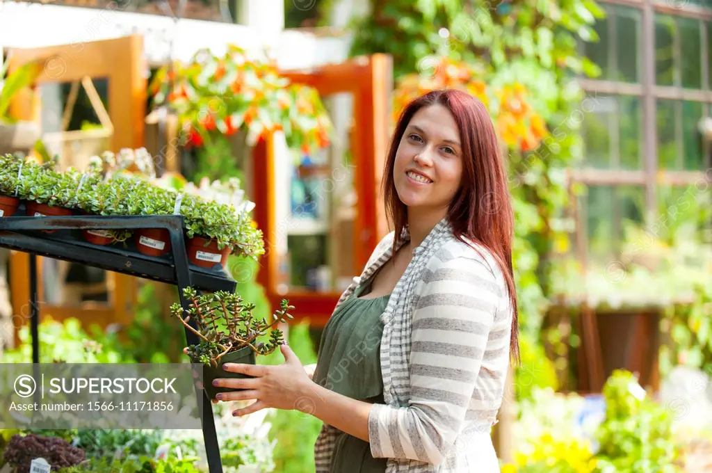 A 24 year old brunette woman shopping in a plant nursery