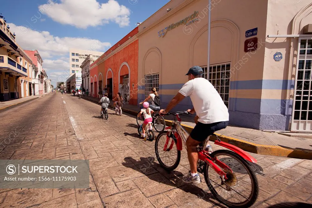 Family members riding on bikes as sunday activity on the street which is closed to the cars every sunday, Merida, Yucatan, Mexico, North America.