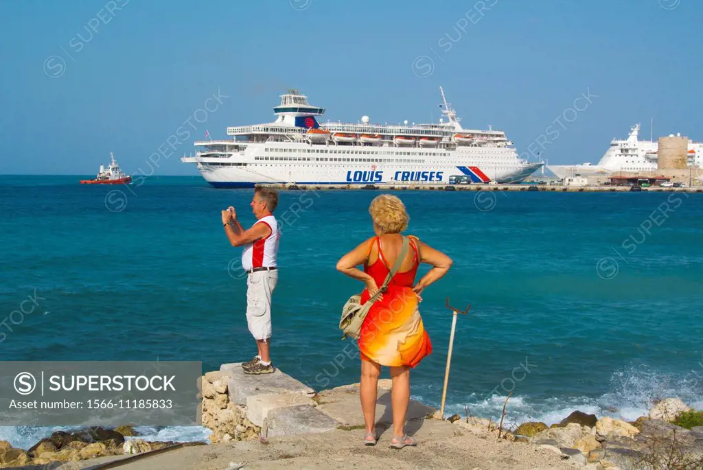 Tourists at Kolona harbour area, in front of cruise boats, Rhodes town, Rhodes island, Dodecanese islands, Greece, Europe.