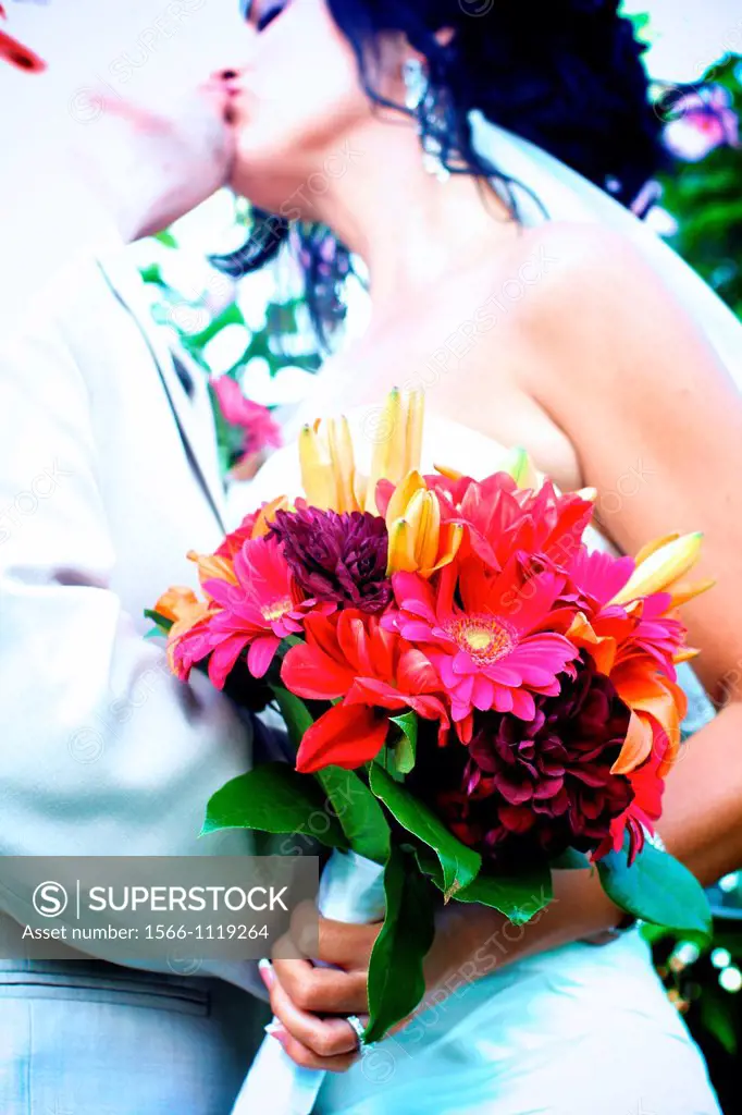 bride groom kissing embracing with bouquet after wedding