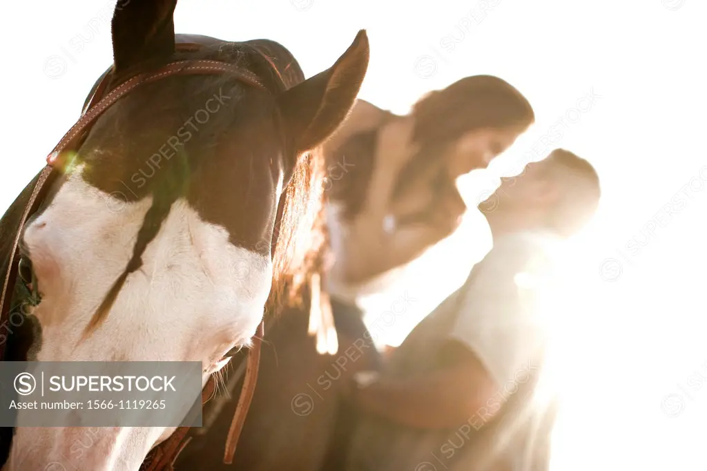 happy engaged pair kissing at sunset riding a horse