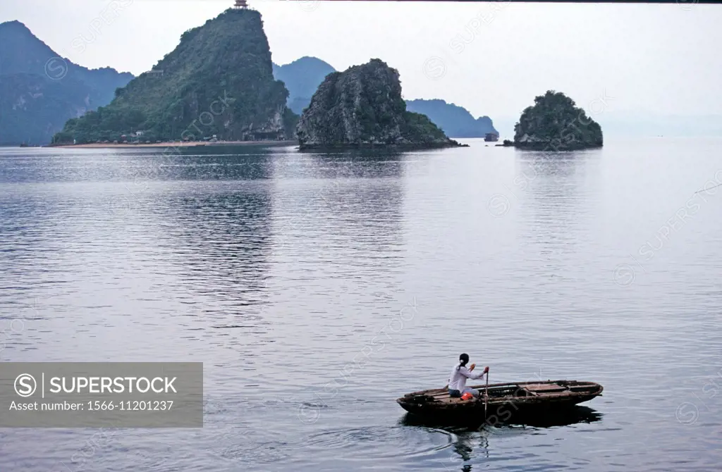Woman rowing a boat in H Long Halong BayUNESCO World Heritage Site Vietnam