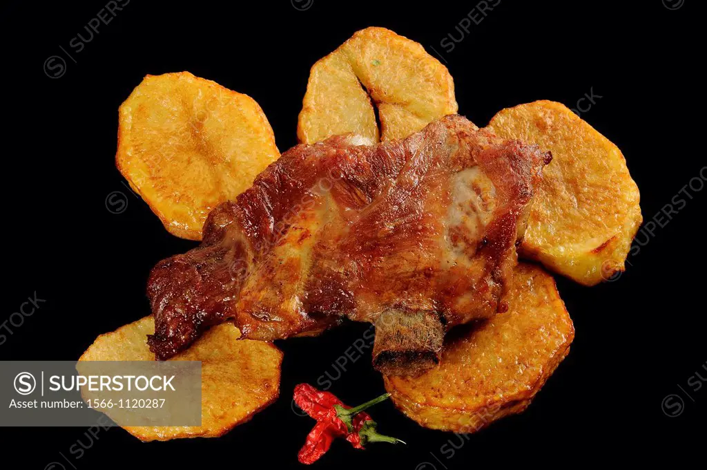 roast ribs and potatos on black plate with red hot pepper
