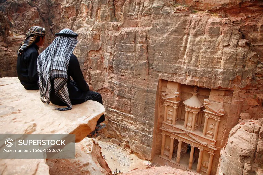 Bedouins sitting on top of a cliff looking down to the Treasury El Khazneh, Petra, Jordan