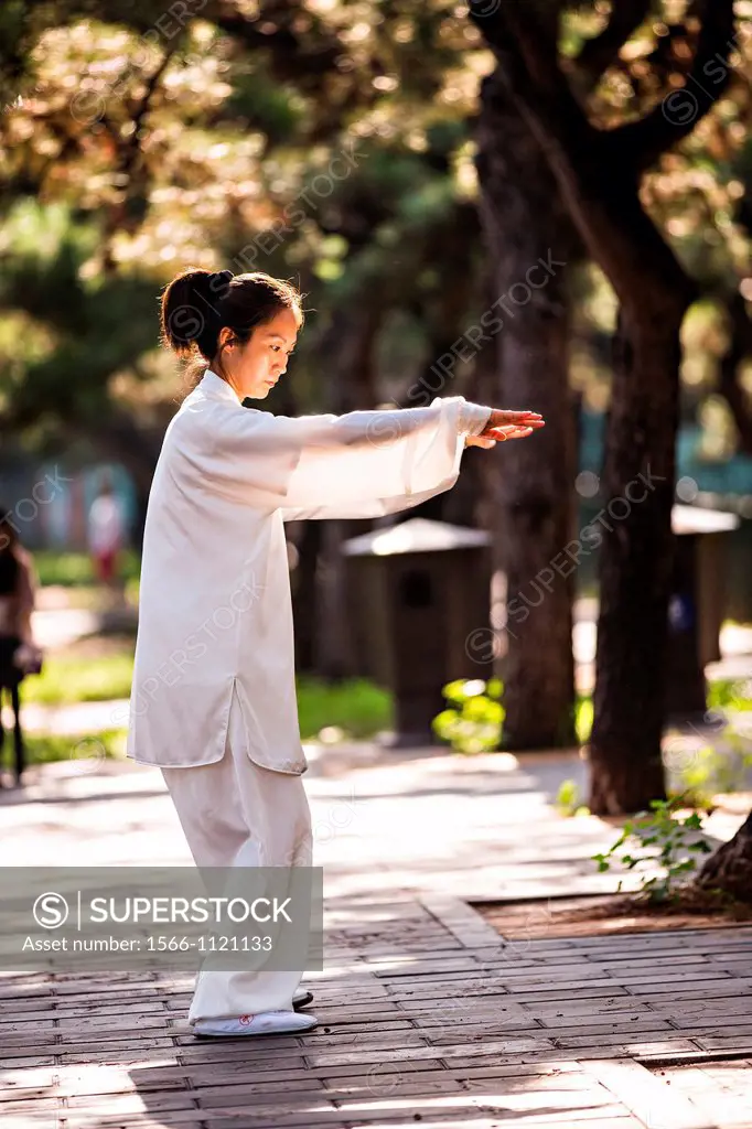Chinese woman practices tai chi martial arts exercise early morning at the Temple of Heaven Park during summer in Beijing, China