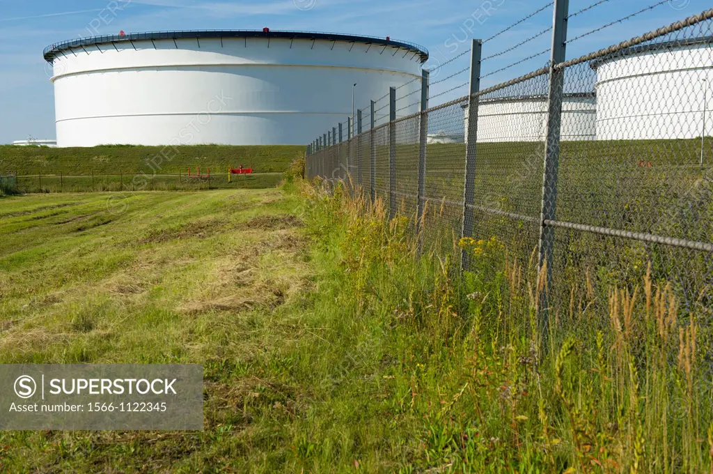 Europoort, Rotterdam, Netherlands. Storage-tanks for oil, fuel and chemicals behind a meadow in Rotterdam harbor.