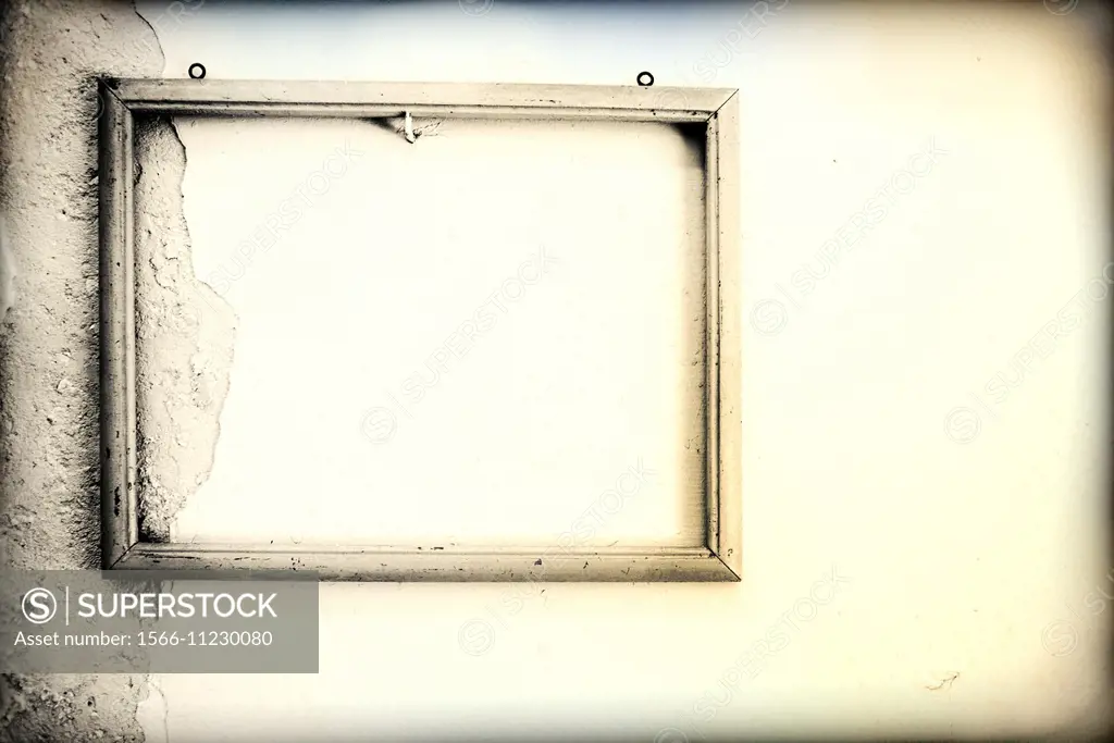 Old empty frame hanging on a white wall