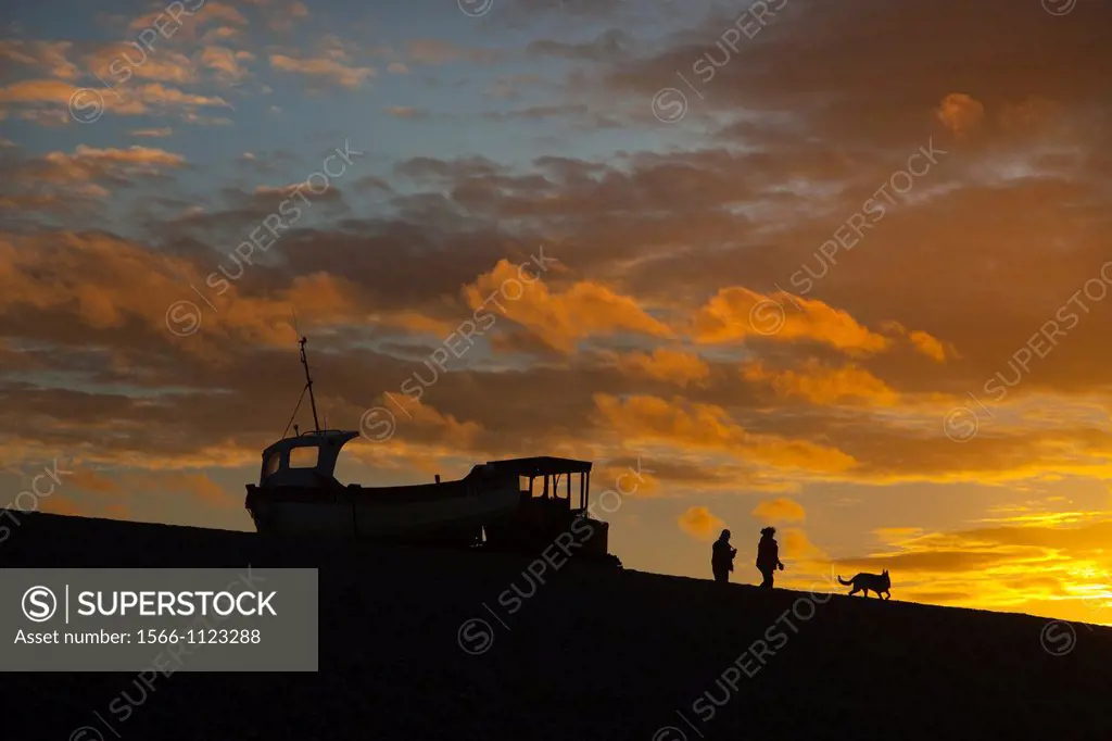 Fishing boat and walkers at sunset Weybourne Beach UK October