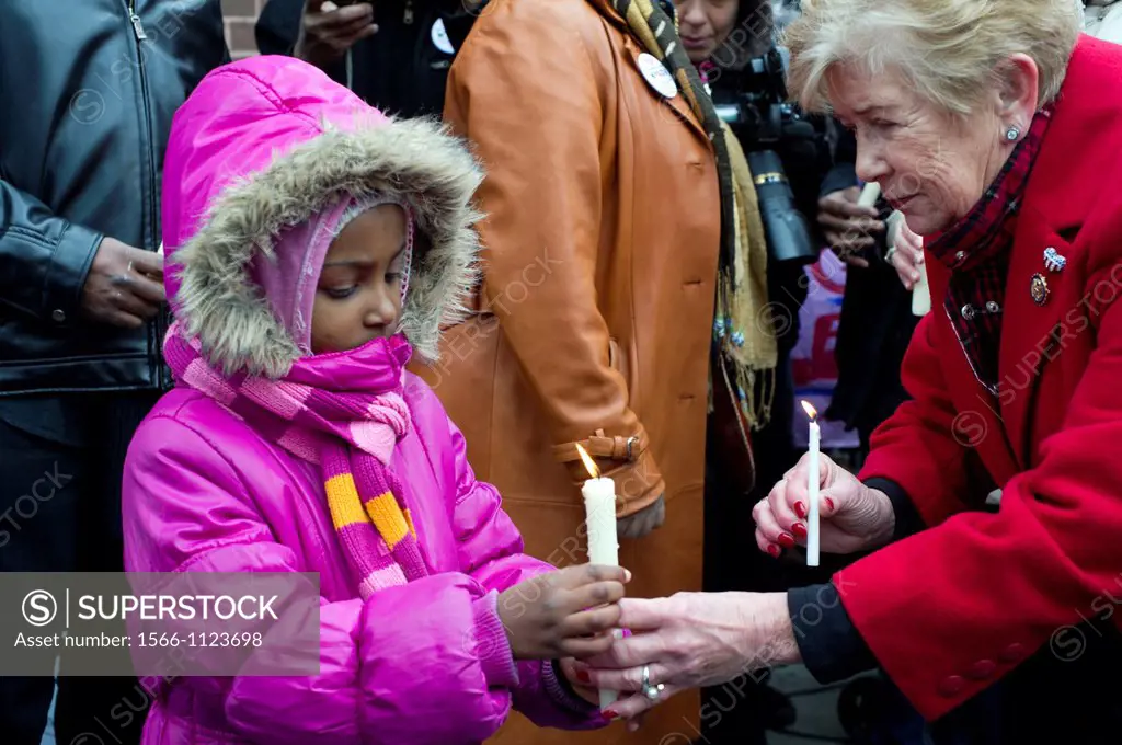 Destiny Walker age five, left, holds a candle for a victim that was murdered in her apartment building, U S  Representative Carolyn McCarthy, right, h...