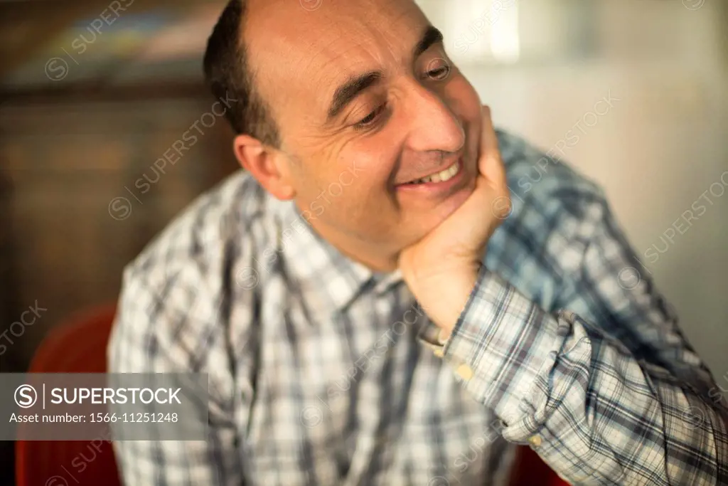 40-year-old Caucasian man, with hand on his chin, smiling and with positive attitude.