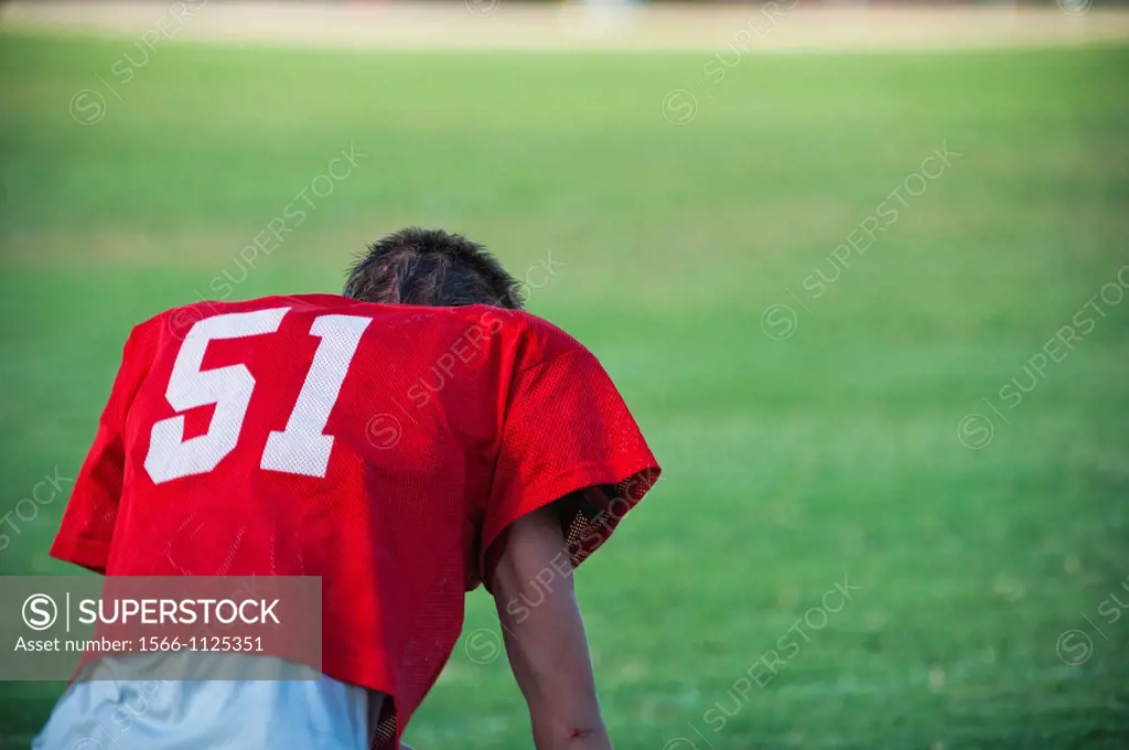 Back side of exhausted American football player without helmet