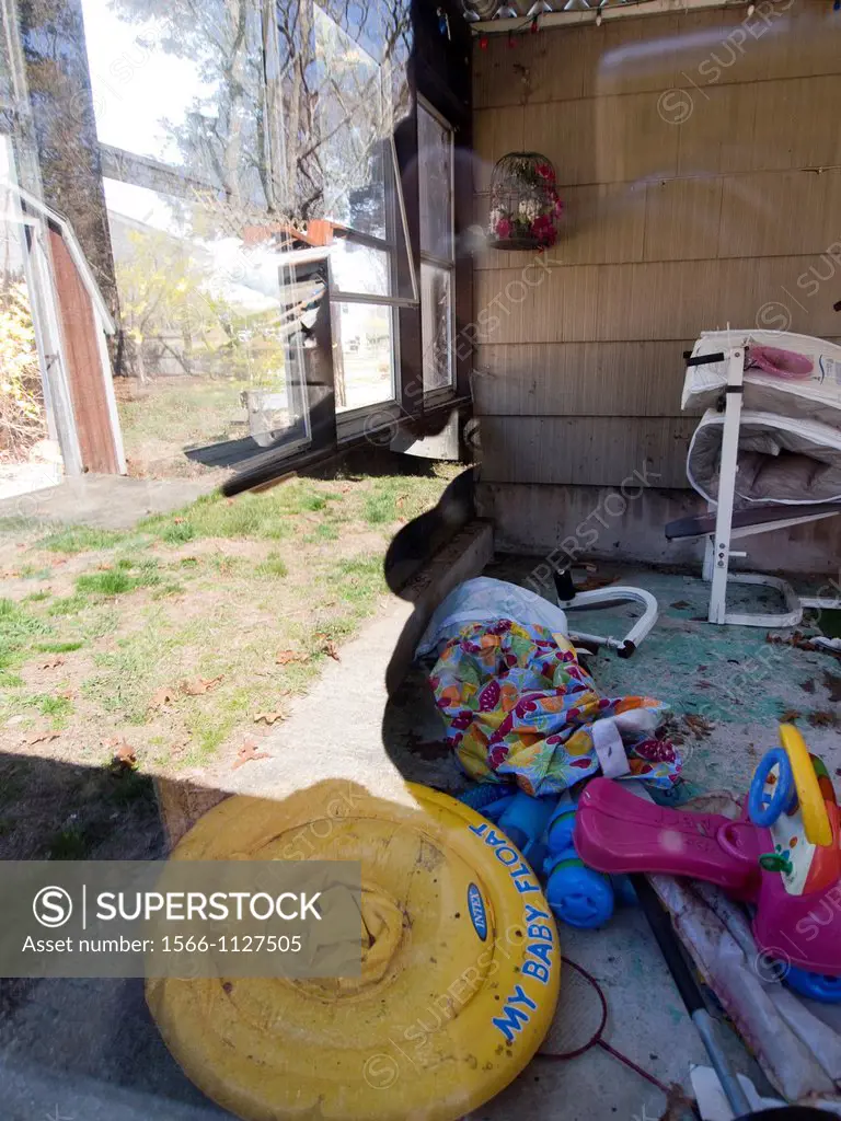 Outdoor junk with pool in window reflection at a foreclosed home in Warwick, Rhode Island
