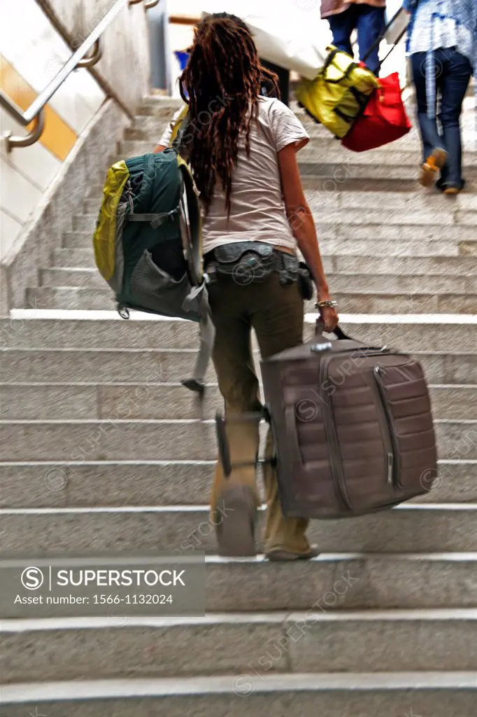 travellers with luggage climbing up stairs to get to railway platform, main railway station in Geneva - Cornavin, Switzerland