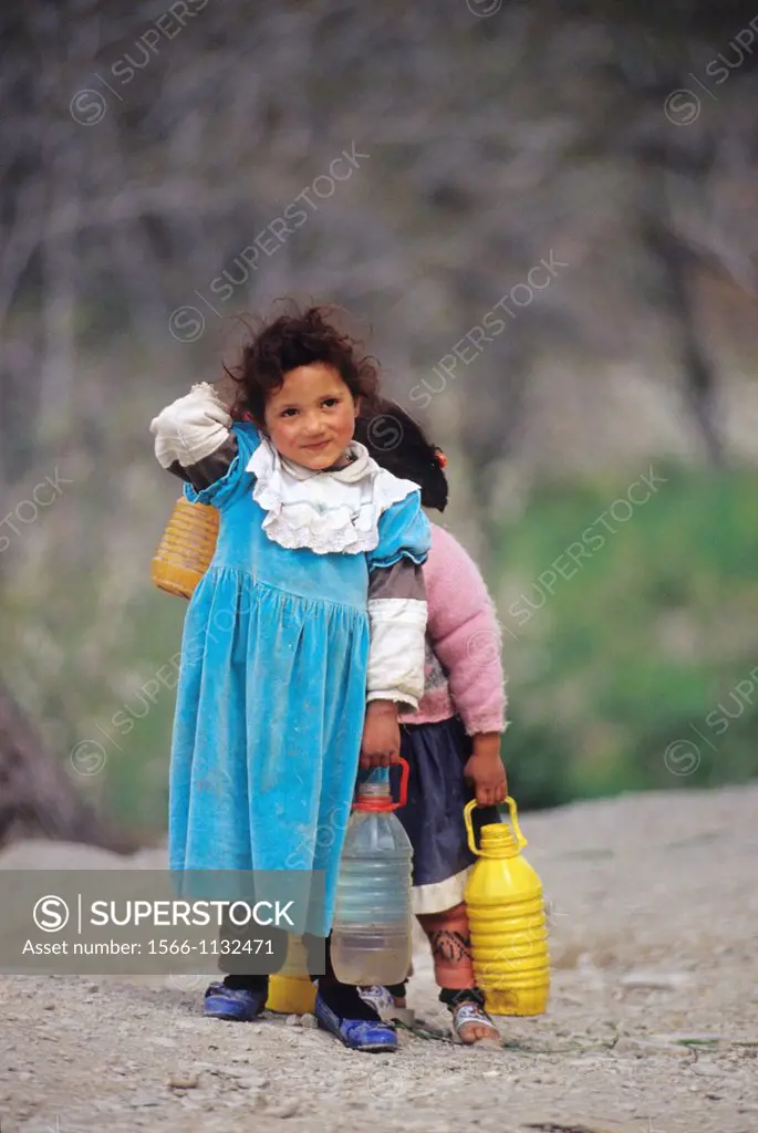 little girl carrying water bottles from a fountain, High Atlas, Morocco, North Africa