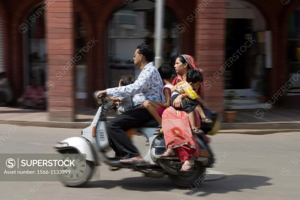 family riding on scooter in a street of Delhi, India, Asia