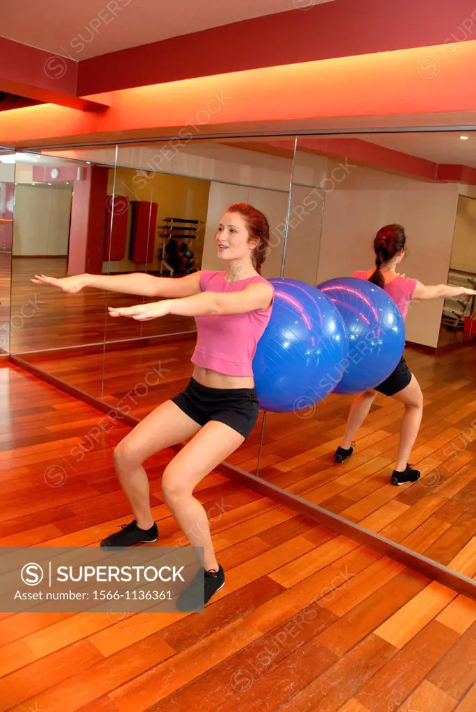 Woman using an exercise ball in a gym  These balls are used when exercising because their inherent instability causes more of the body´s muscles to re...