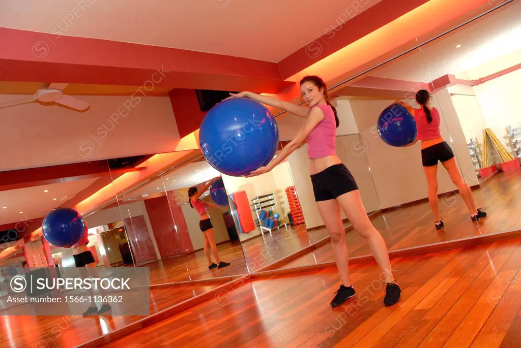 Woman using an exercise ball in a gym  These balls are used when exercising because their inherent instability causes more of the body´s muscles to re...