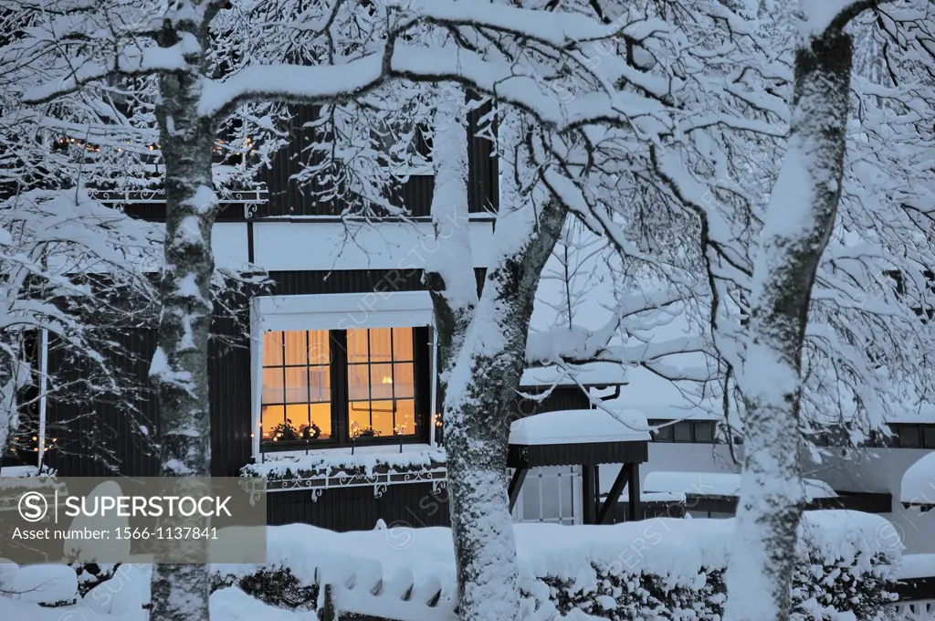 house covered with snow and an illuminated window