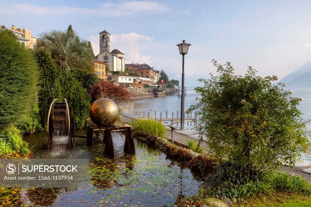 Overlooking the old town of Brissago in Ticino, Switzerland, with a fountain and a sculpture in the foreground