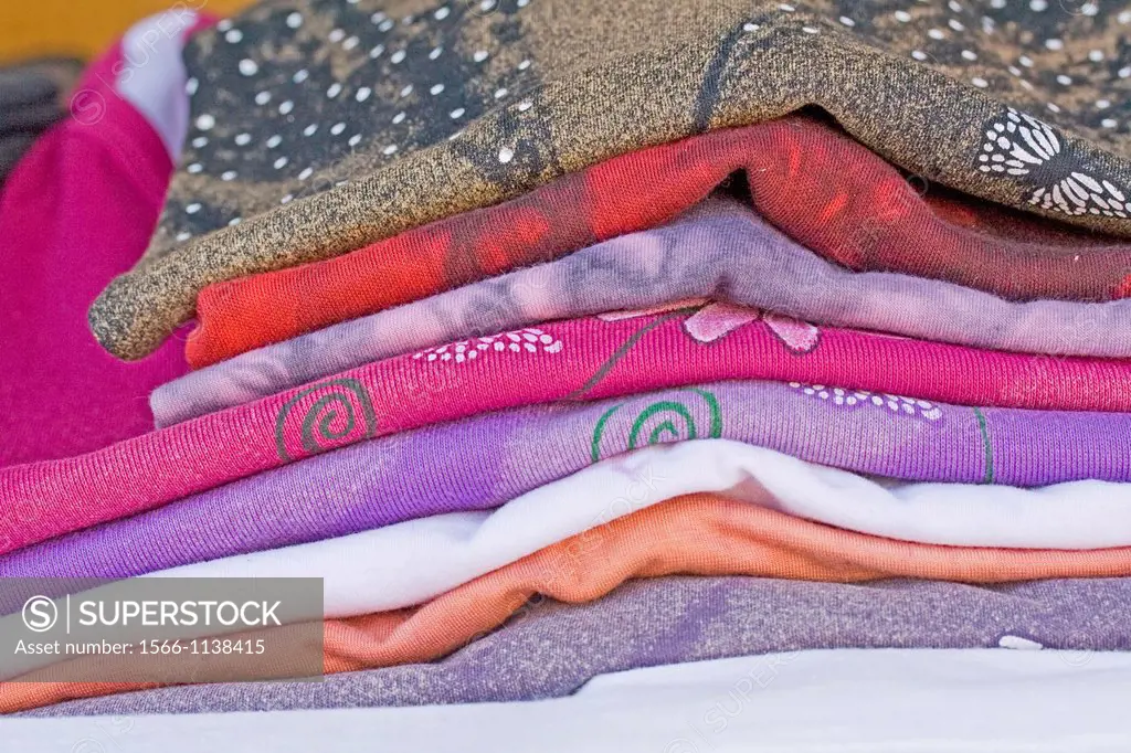 Handmade knitted clothes in a farmers market  Neatly stacked shirts are displayed in farmers market with homemade house linens  Folded and stacked nea...