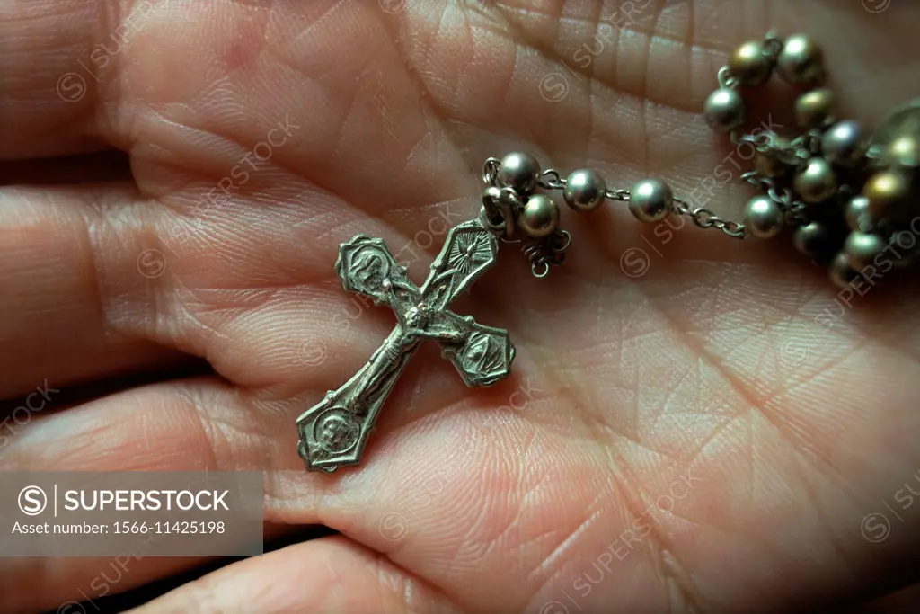 closeup of an adult hand and rosary with a crucifix