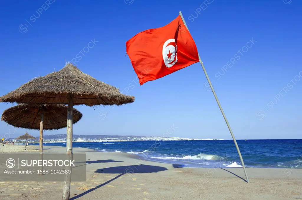 North Africa, Tunisia, Cape Bon, Hammamet. Tunisian flag floating in the wind on the beach of Hammamet.