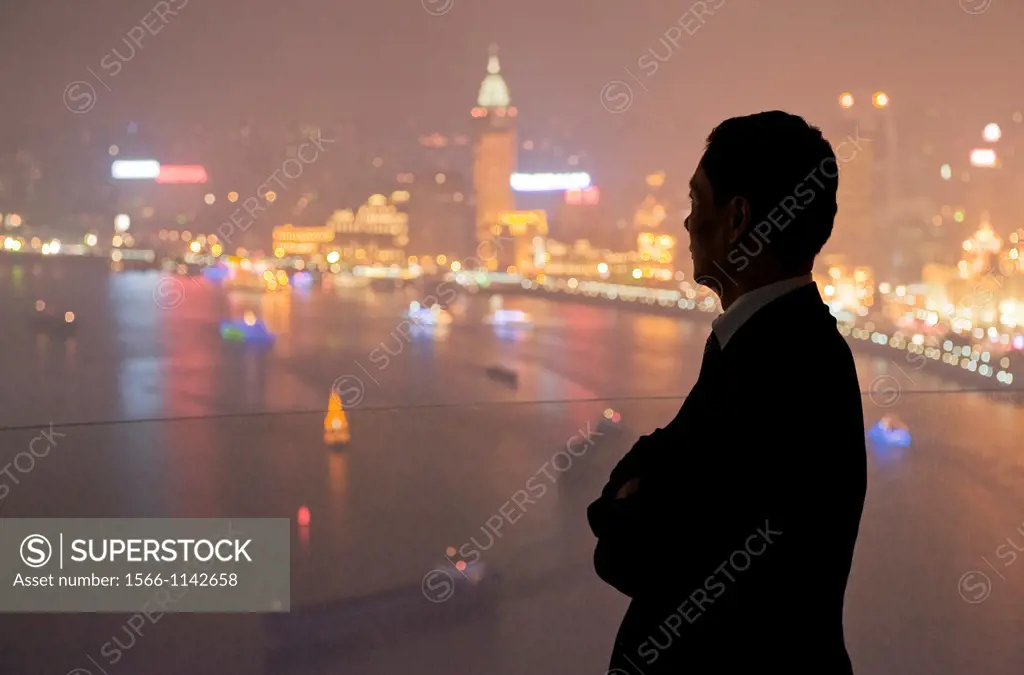 The silhouette of a man looking out to the illuminated Pudong skyline from the Hyatt on the Bund Hotel