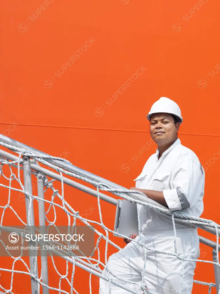 A portrait of a inspector at a commerical container and Palm Oil port in Johor, Malaysia walking up a stairway to the deck of a ship
