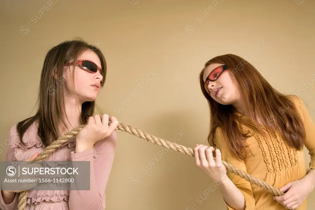 Preteen girls, wearing sunglasses, pulling on a rope