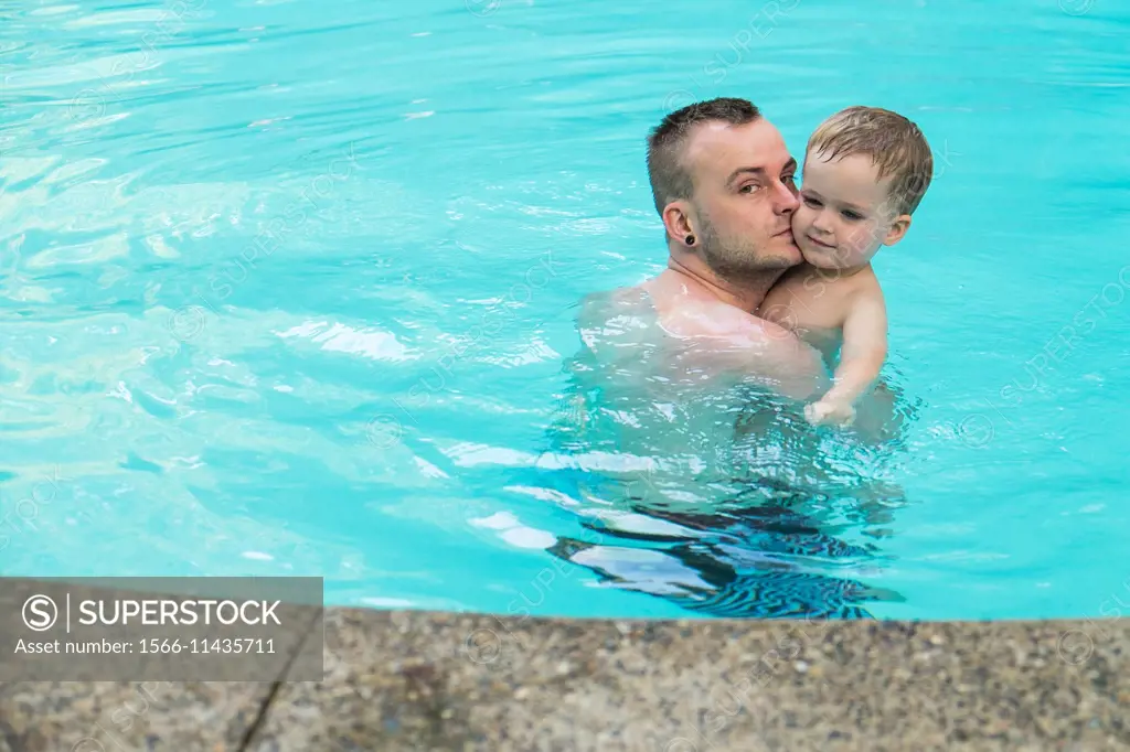 Father with his toddler boy in the swimming pool.