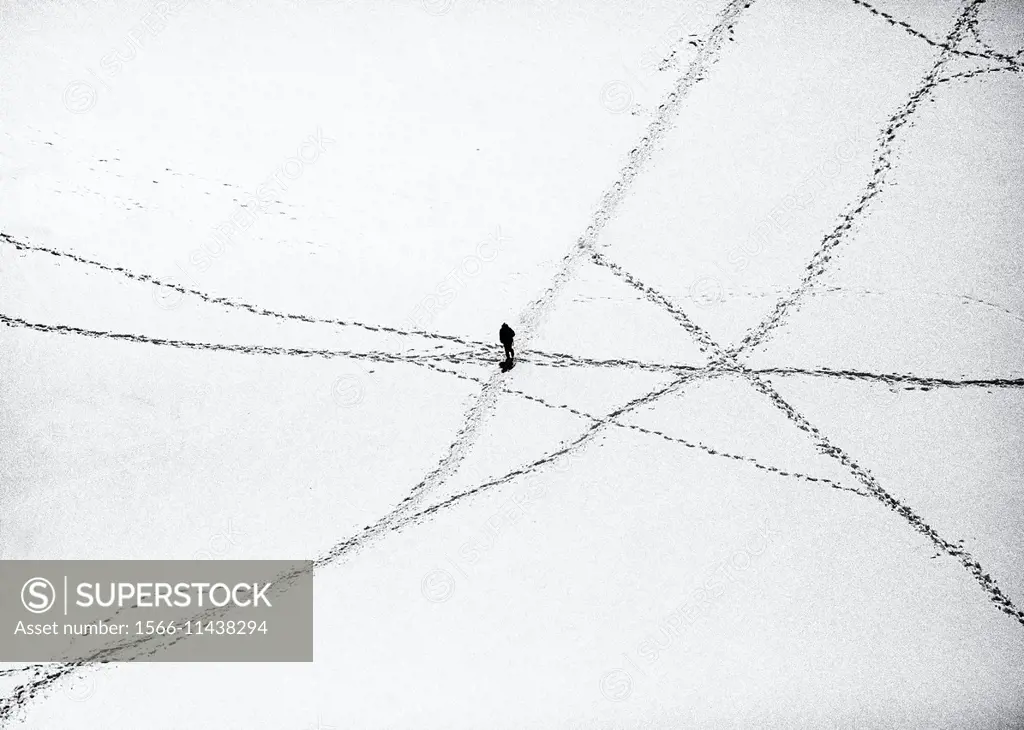 single person between roads created by footprints in snow, view from above, French Alps, France