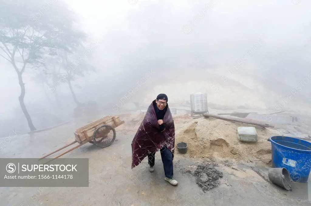 A man wrapped in a blanket and an old pull cart at the San Huang Zhai Monastery on Song Mountain, China