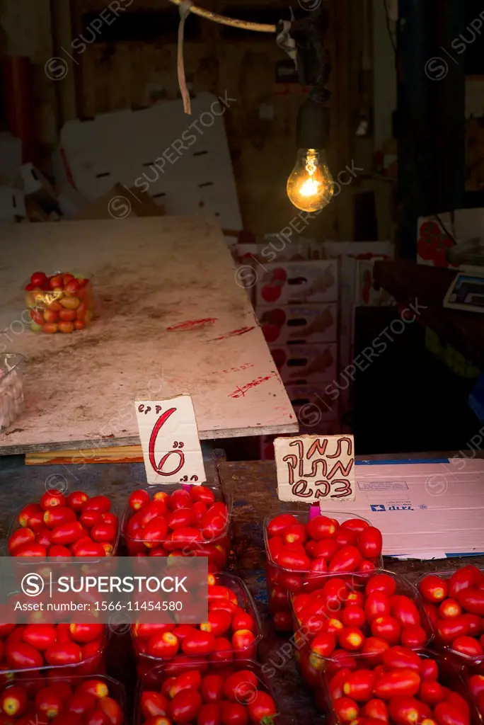 Closeup of baskets with ecological tomatoes with a light bulb lit in a market in Tel Aviv, Israel.