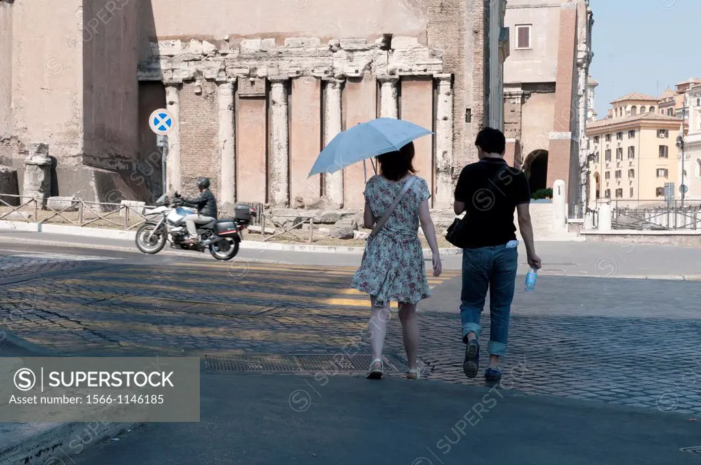 Europe, Italy, Rome  Young Roman couple walks towards ancient columns built into newer construction near the Teatro di Marcello Theatre of Marcellus