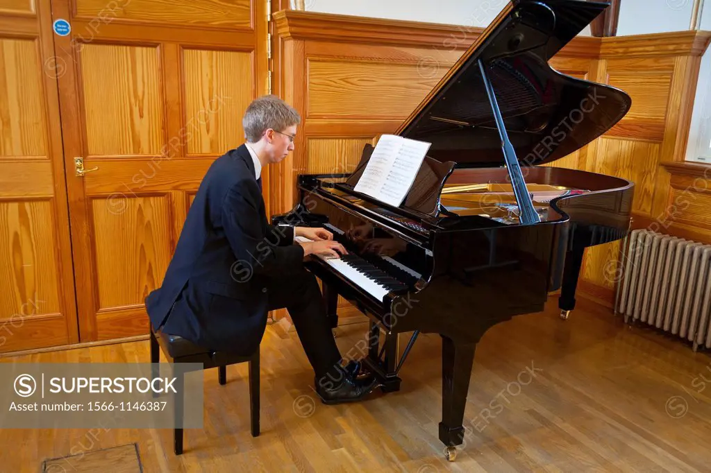 Young man playing a grand piano at the Royal College of Music, London, England