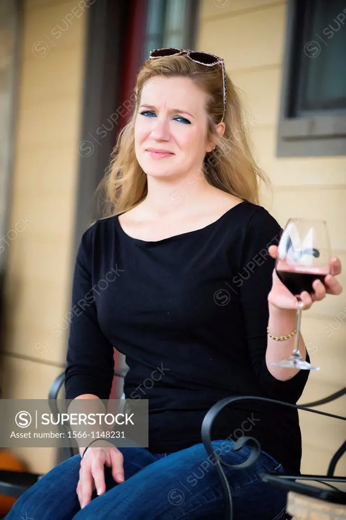 Woman holding a glass of red wine while sitting in front of her house