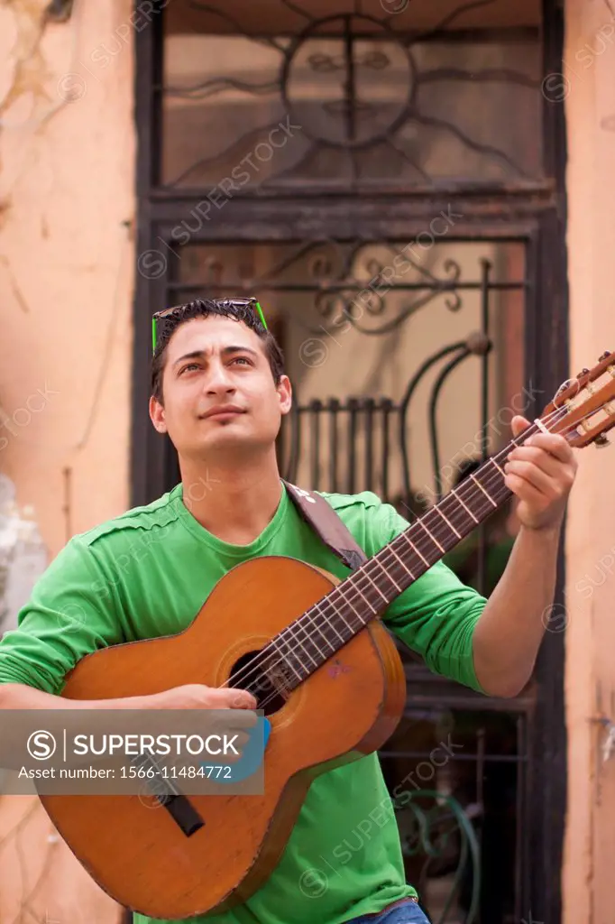 A young man is playing the guitar in the streets of Plaka. Athens, Greece.