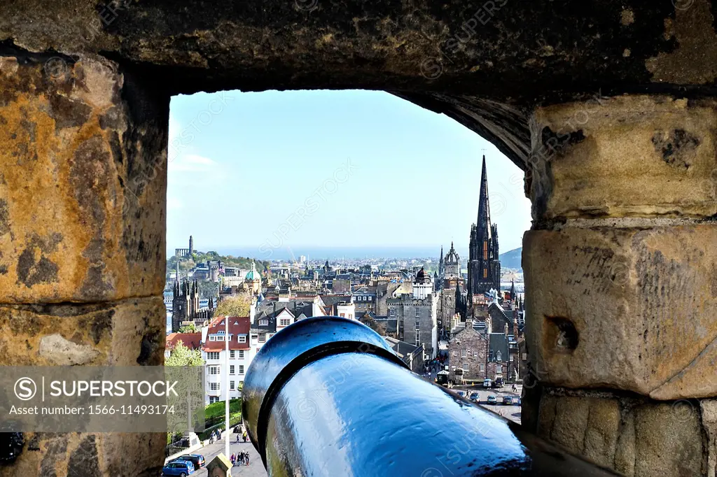 A cannon in a turret, with a view of the spire of Edinburgh Cathedral against the rest of the city.