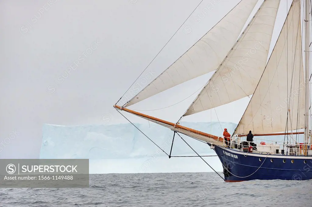 Greenland, Melville Bay, Schooner Rembrandt Van Rijn cruising along a 50 m high iceberg