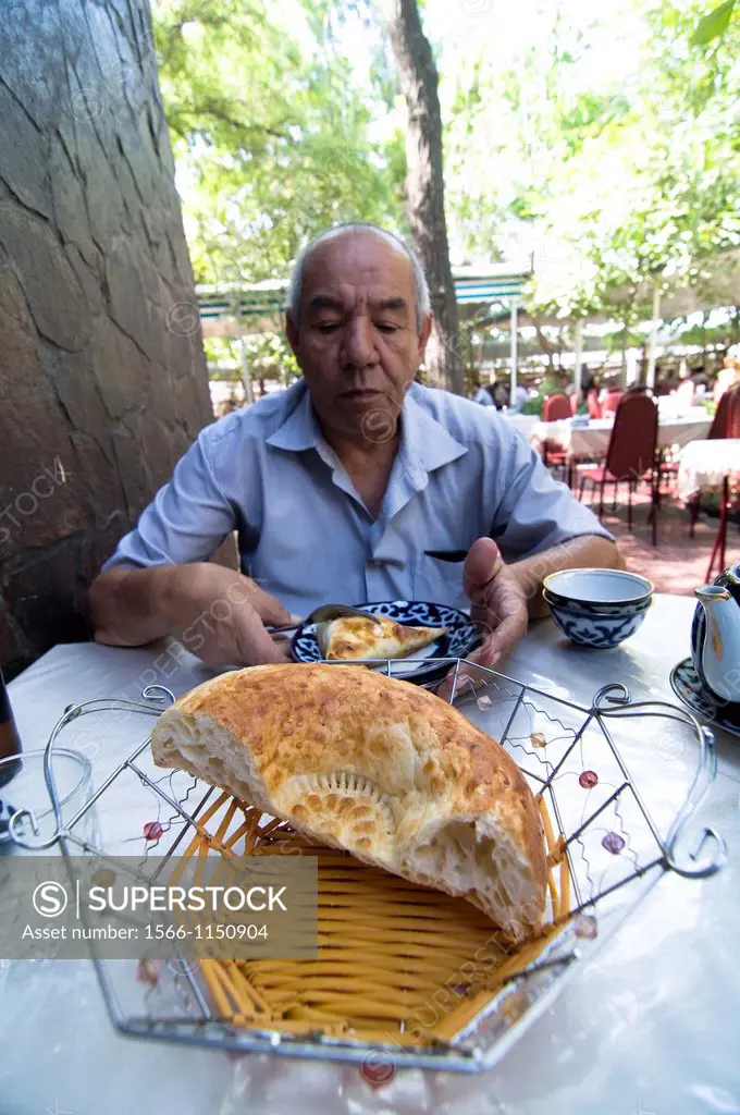 An Uzbek man enjoying a traditional Uzbek lunch  Samsa, Nan bread and a cup of tea