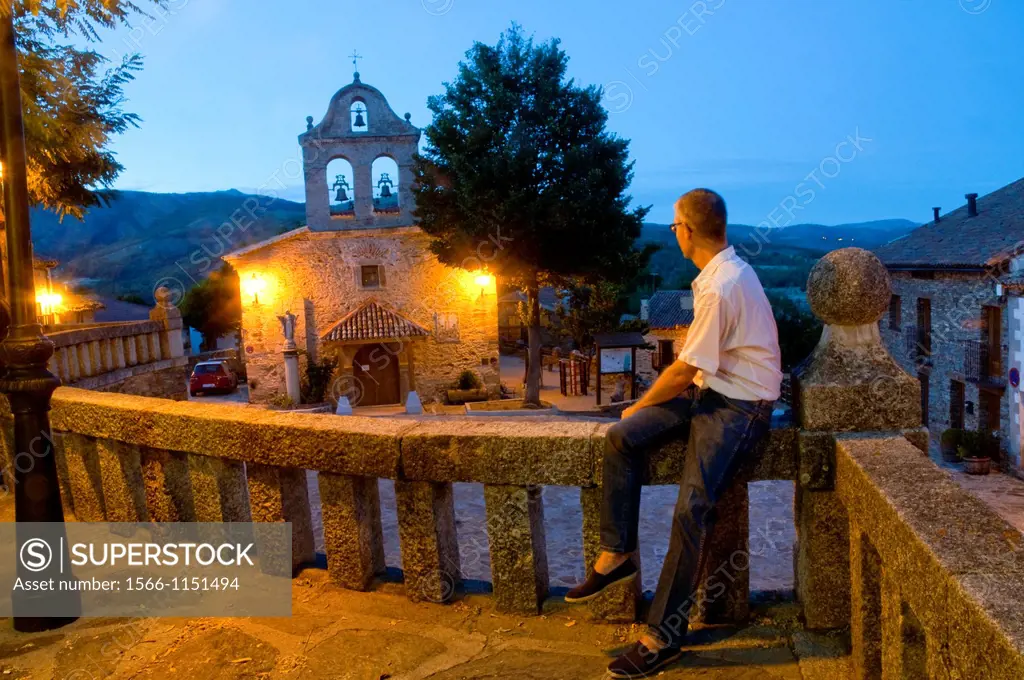 Man sitting on stone banister at evening. La Hiruela, Madrid province, Spain.