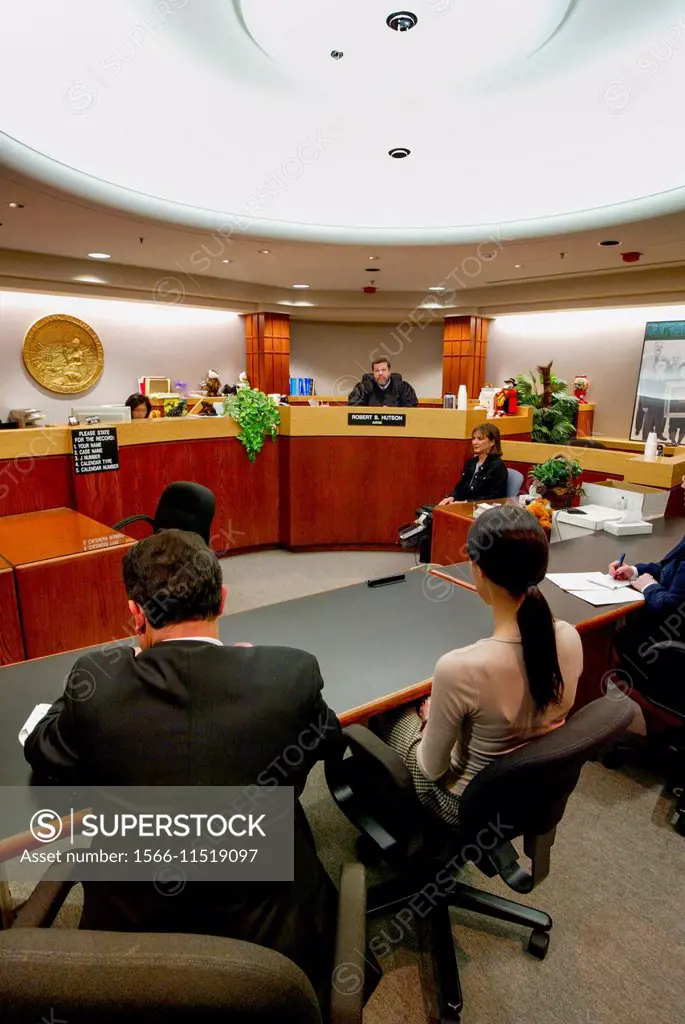 A teenage Hispanic defendant appears before a juvenile court in Orange, CA. Note African American judge, lawyer at left, and court reporter.