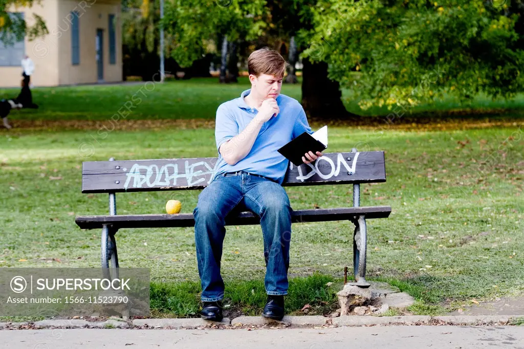 Young man sitting on a park bench .